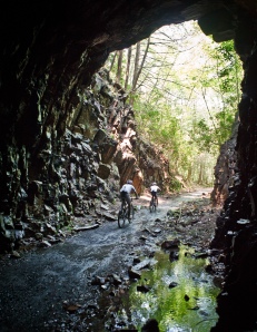 Mountain bikers riding through abandoned railroad tunnel in Coburn, PA by Abram Eric Landes